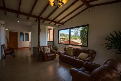 a living room with leather furniture and a large window at Finca Hotel 12 Palmas- Aeropuerto JMC in Rionegro
