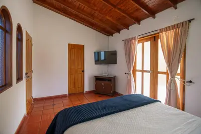 a bedroom with a bed and a flat screen tv at Finca Hotel 12 Palmas- Aeropuerto JMC in Rionegro