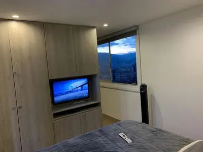 a bedroom with a flat screen tv and a window at 1213 Suite Moderna - Confort zona rosa poblado in Medellín