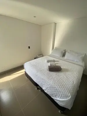 a bedroom with a white bed with a towel on it at 1213 Suite Moderna - Confort zona rosa poblado in Medellín
