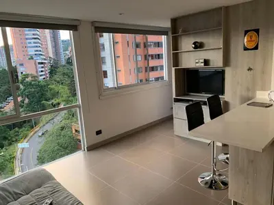 a living room with a desk and a large window at 1213 Suite Moderna - Confort zona rosa poblado in Medellín