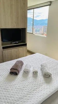 a bedroom with a bed with two towels and a television at 1213 Suite Moderna - Confort zona rosa poblado in Medellín
