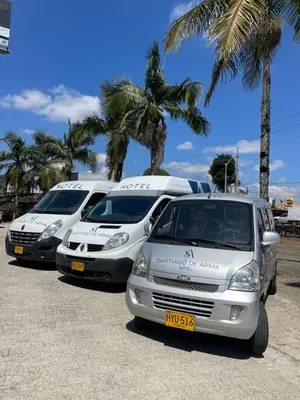 three vans parked in a parking lot with palm trees at Hotel Santiago de Arma in Rionegro