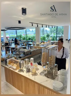 a woman standing behind a counter in a restaurant at Hotel Santiago de Arma in Rionegro