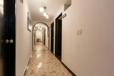 a hallway with a tile floor and a long corridor at Hotel De León Estadio in Medellín