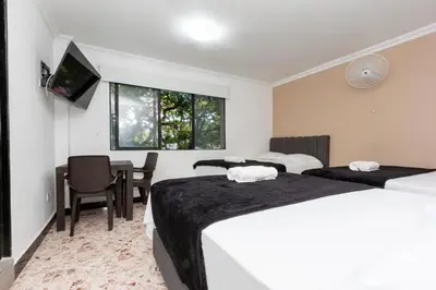 a hotel room with two beds and a table at Hotel De León Estadio in Medellín