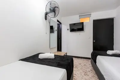 a hotel room with two beds and a flat screen tv at Hotel De León Estadio in Medellín