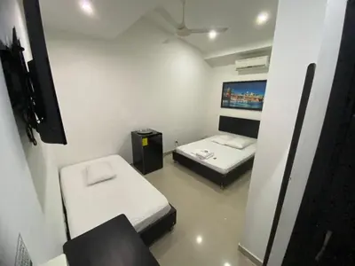 a small room with two beds and a tv at Hotel Malecon Puerto Berrio in Puerto Berrío
