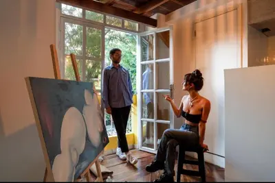 a man and a woman in a room with a painting at Estudio Duplex Vintage en el Centro para 4H Atelier in Medellín
