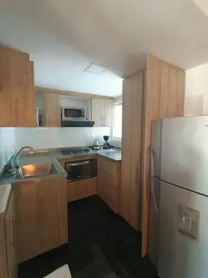 a kitchen with wooden cabinets and a stainless steel refrigerator at Estudio Duplex Vintage en el Centro para 4H Atelier in Medellín