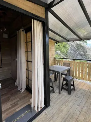a wooden patio with a table and chairs on a deck at La Peña Cabins - Ebéjico in Ebéjico