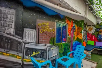 a mural on a wall with chairs and a tv at Blue Coast Hostal in Medellín
