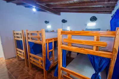 a room with two bunk beds and a table and chairs at Blue Coast Hostal in Medellín