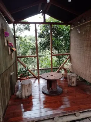 a porch with a table and some trees at Sukha Glamping in Rionegro