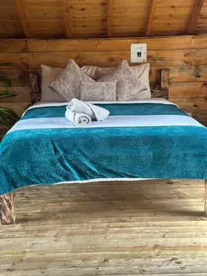 a bed with a green blanket and a towel on it at Sukha Glamping in Rionegro