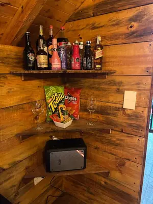 a bar with a wall with bottles and glasses at Sukha Glamping in Rionegro
