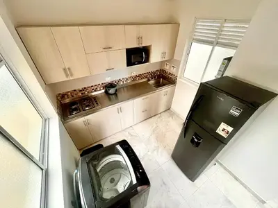 a small kitchen with a black refrigerator and a washer at La Posada de Miguel in Medellín