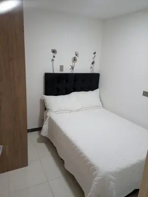 a bedroom with a white bed with a black headboard at Apartamento acogedor en Medellín in Medellín