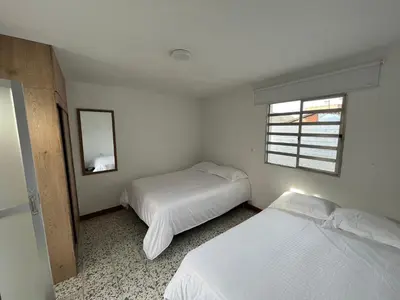 a bedroom with two beds and a window at Casa Blanca Hostal in Rionegro