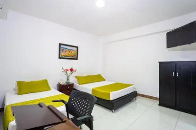 a bedroom with two beds and a desk and a chair at Ayenda 1234 Imperio 70 in Medellín