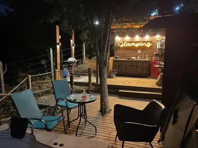 a table and chairs on a deck at night at Entre-pinos Glamping WiFi Vista 360º in Guarne