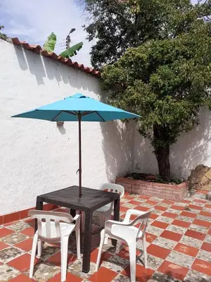 a table with a blue umbrella and two chairs at Hospedaje casa completa Honda Tolima in Honda