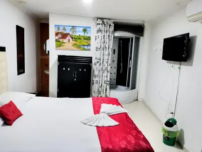 a bedroom with a white bed and a red blanket at Hotel flamingo real T in Mariquita