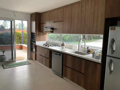 a kitchen with wooden cabinets and a sink and a refrigerator at Hermosa casa de campo en ambiente tranquilo. in Rionegro