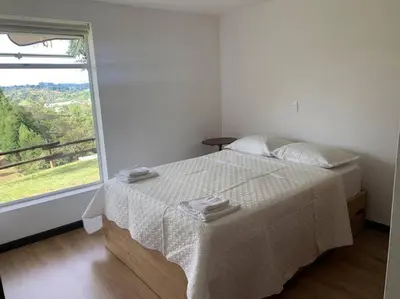 a white bedroom with a bed and a window at Hermosa casa de campo en ambiente tranquilo. in Rionegro
