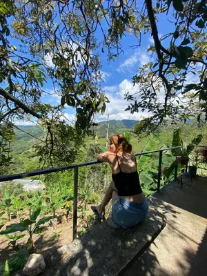 a woman sitting on a balcony looking at the mountains at Tierra Mágica eje cafetero in Manizales
