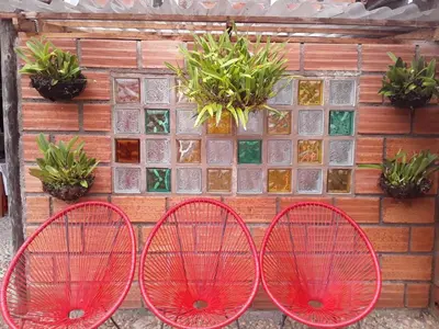 three red chairs in front of a wall with plants at Hotel Kantarrana Urbana Jardin in Jardin