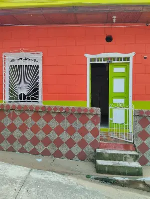a red building with a green door and a window at Casa Mamá Chelita in Titiribí