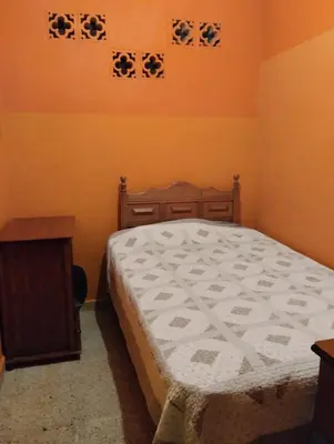 a bedroom with a bed and a wooden table at Casa Mamá Chelita in Titiribí