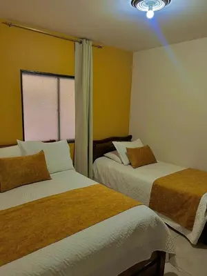 two beds in a room with yellow walls at Hotel Dorado Jardín in Jardin
