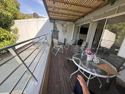 a person sitting on a balcony with a table and chairs at Apartamento 2 habitaciones aire acondicionado en Sopetran Unidad res Piscinas sol y descanso in Sopetran