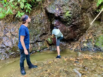 two people standing in the water in a stream at Aldea Sabatinga in Manizales
