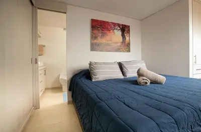 a bedroom with a blue bed and a painting on the wall at Elegante Apto en el Poblado! Vista Fabulosa in Medellín