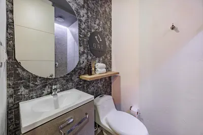 a bathroom with a sink and a mirror and a toilet at One Apartments Laureles in Medellín