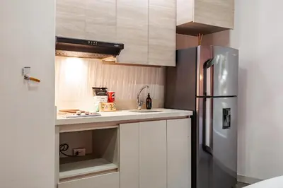 a kitchen with white cabinets and a stainless steel refrigerator at One Apartments Laureles in Medellín
