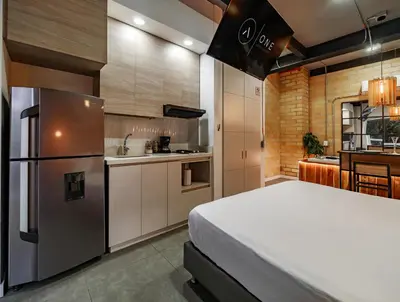 a bedroom with a large bed and a kitchen at One Apartments Laureles in Medellín