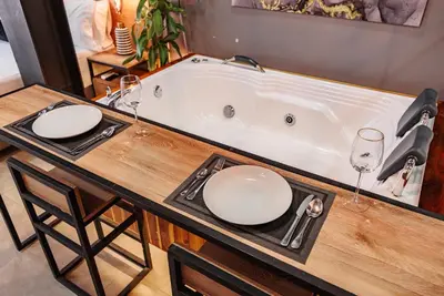 a bath tub with two wine glasses and a table at One Apartments Laureles in Medellín