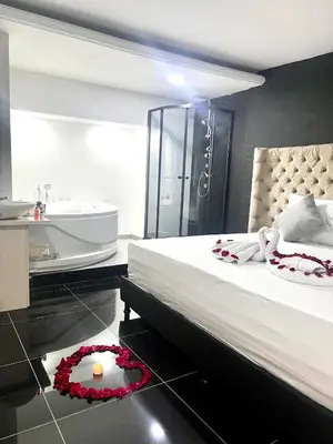 a bedroom with a large bed and a bathroom with a sink at Orbe Hotel Medellín in Medellín