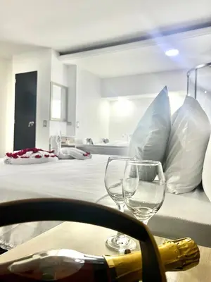 two wine glasses sitting on a table next to a bed at Orbe Hotel Medellín in Medellín