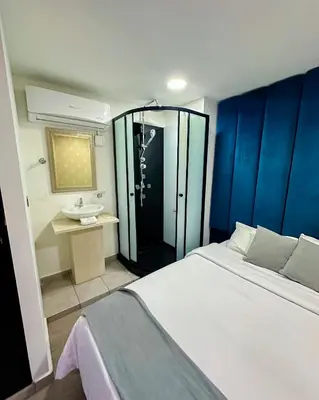 a bedroom with a bed and a shower and a sink at Orbe Hotel Medellín in Medellín