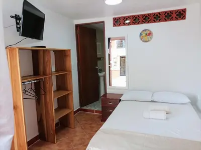 a bedroom with a bed and a tv and a shelf at Petroglifo Room Támesis in Támesis