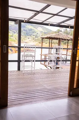 two white chairs and a table on a deck at Hotel Casa Linda Guatape in Guatapé
