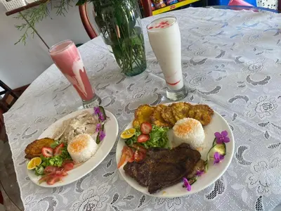 a table with two plates of food and a drink at Hotel Casa Linda Guatape in Guatapé