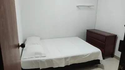 a small bedroom with a white bed and a dresser at Habitación central con cama doble #2 in Medellín