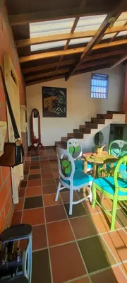 a living room with chairs and a table and a room with at Casa Hotel los Patios in Jericó