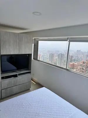 a bedroom with a flat screen tv and a large window at 2511 Suite Moderna y de lujo con la mejor vista a la ciudad - Poblado Medellín in Medellín